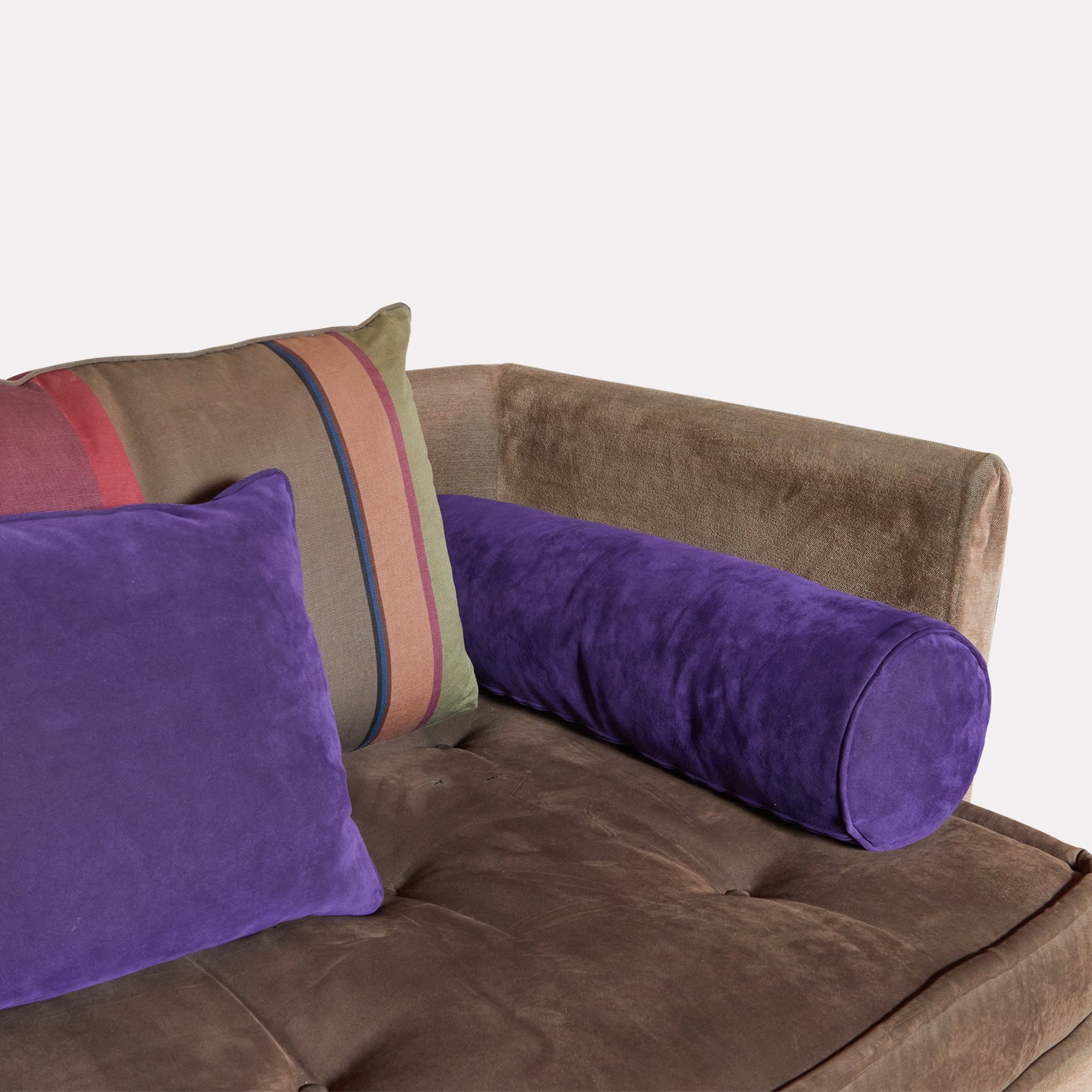 Detail of sectional sofa showing a bolster cushion and 2 back cushions in shades of aubergine, taupe and burgundy 